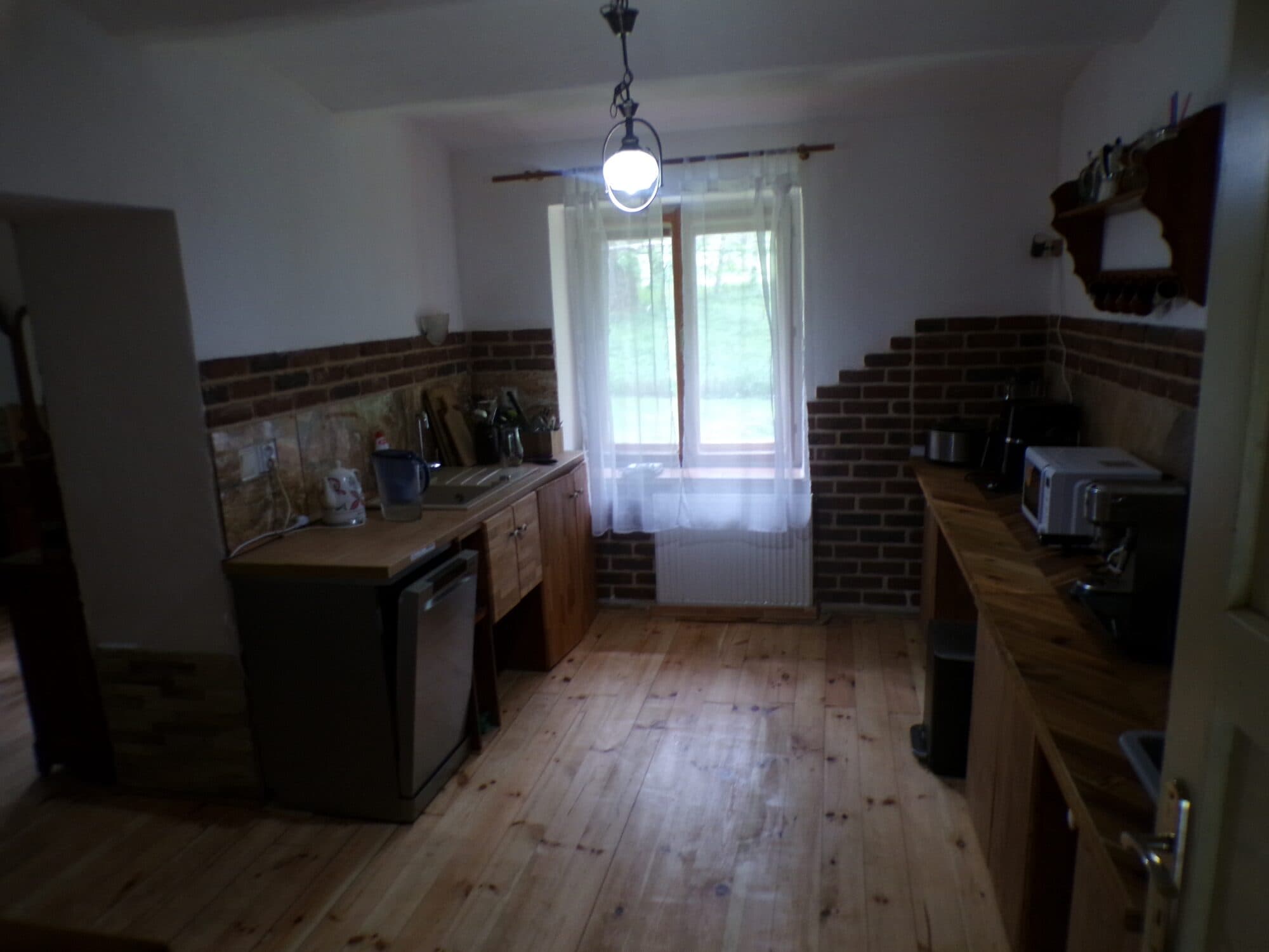 Plně vybavená kuchyně s dřevěnou linkou, myčkou, troubou a oknem do zahrady